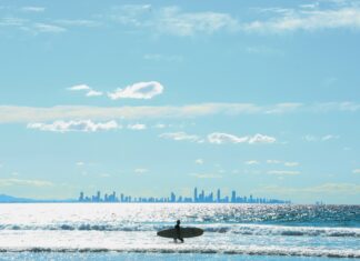 A tour around Coolangatta with cherrypicked must-do activities Coolangatta beach surfer with Gold Coast in the backdrop