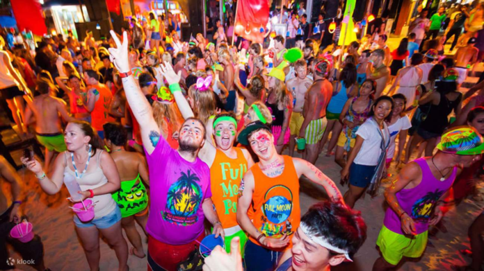 Party revelers wearing colorful clothes and bands at the full moon party Koh Phangan